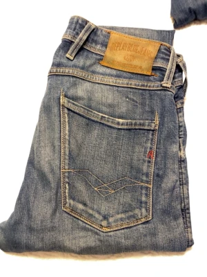 Blå Replay jeans med raka ben - Säljer ett par klassiska blå jeans från Replay med raka ben och snygga slitningar. Jeansen har fem fickor, normal midja och detaljerade sömmar på bakfickan. Perfekta för dig som gillar en avslappnad men stilren look.Skick 5,5/10