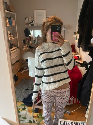 Vit stickad tröja med svarta ränder - Säljer en vit stickad tröja med svarta horisontella ränder. Tröjan har rund halsringning, långa ärmar och en avslappnad passform. Perfekt för dig som gillar en enkel men snygg stil. Materialet känns mjukt och bekvämt.