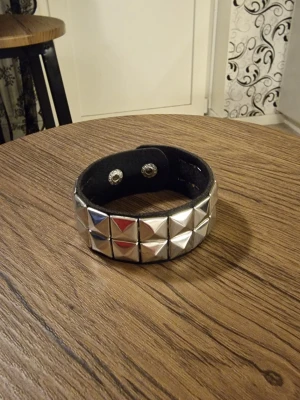 Armband punk pyramidnitar - Armband punk med pyramidnitar. Punk gothic style. Dubbelradigt kvadratiskt PU-läderarmband. Hip-hop, rock Musik festival, party, pararmband. Längd 22 cm. Bredd 2,8 cm.