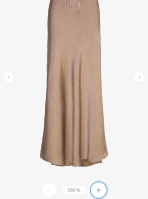 Beige långkjol från A View - Säljer en beige långkjol från A View i storlek 42. Kjolen har en snygg satinkänsla med  knytband i midjan. Den har en mjuk, flowy passform och passar perfekt till både sneakers och boots. Fin både till stickat och till fest!