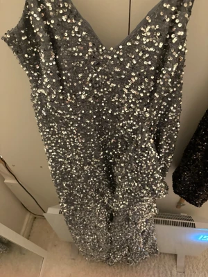 Otroligt snygg, glittrig klänning - Snygg lång klänning täckt av silverfärgade paljetter med v-ringning och smala axelband. Klänningen har en figurnära passform och ger ett riktigt statement-intryck. Perfekt för dig som vill sticka ut på festen! Har tyvärr inte storleken men passar M-XL! Kontakta för fler bilder!