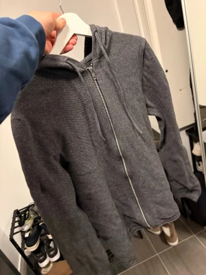 Mörkgrå zip hoodie - Mörkgrå hoodie med dragkedja framtill och huva. Tillverkad i ett mjukt, stickat Matrial.