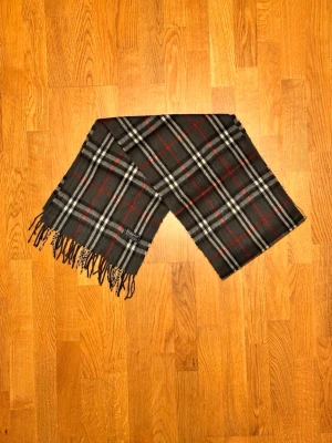 Grå Burberry halsduk - Säljer en grå halsduk från Burberry. Halsduken är i bra skick och är gjord i 100% lamull. Var inte rädd för några frågor. Pris diskuteras inte!