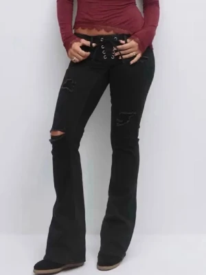 Jeans ifrån gina 14 + - Svarta jeans med bootcut-passform och cool snörning i midjan. Jeansen har slitna detaljer och hål på ena knät för en edgy look. Perfekta för dig som gillar en trendig och avslappnad stil. Storlek: S 