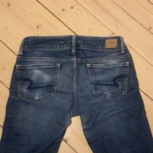 Bootcut jeans från American Eagle - Snygga mörkblå jeans från American Eagle med klassisk femficksdesign och dubbla knappar i midjan. Säljer för att de tyvärr var för korta på mig. Jag är 175 så de passar någon runt 160-170🫶🏼