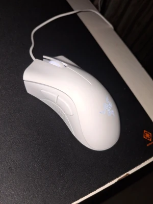 Vit gamingmus från Razer - Säljer en vit gamingmus från Razer med ergonomisk form och sladdanslutning. Musen har två sidoknappar, scrollhjul och den klassiska Razer-loggan som lyser upp. Perfekt för gaming och snabba rörelser på musmattan.