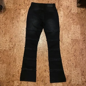 Svarta flare jeans från boohooMAN - Svarta jeans från boohooMAN med flare och paneler med fransade detaljer längs benen. Slim fit och klassisk femficksdesign. Jeansen är tillverkade i jeansmaterial och har en cool, rå look med tvättad finish. W 28 L 32-33