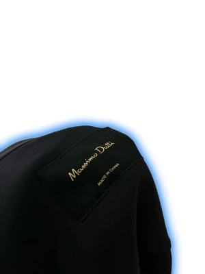 Svart overshirt från Massimo Dutti - Svart overshirt från Massimo Dutti med klassisk krage och dragkedja framtill. Jackan har långa ärmar med knapp vid mudden och är tillverkad i ett mjukt, slätt material som ger en clean och stilren look. Perfekt att slänga på över en t-shirt för en chill vibe.