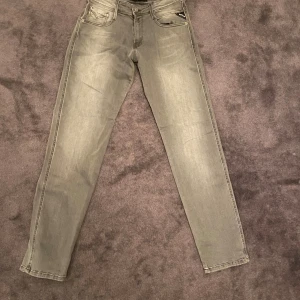Replay Anbass grå slim jeans W28 L30 - Snygga grå jeans från Replay, modell Anbass med slim fit och powerstretch. Klassisk femficksdesign, broderade detaljer på bakfickorna och normal midja. Perfekt passform och stilren look för dig som gillar moderna jeans. Har aldrig använt och lappar sitter kvar!