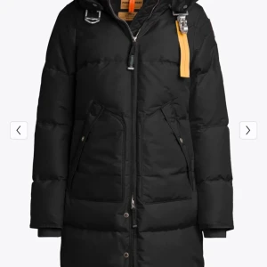 Svart dunjacka från Parajumpers - Snygg svart dunjacka från Parajumpers med huva och dragkedja. Jackan har en gul detalj vid halsen och praktiska fickor med knappar. Perfekt för kalla dagar.