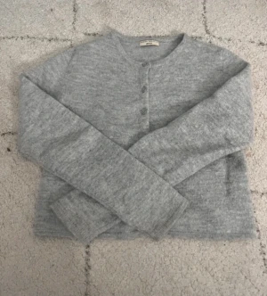 Grå kofta från Gina Tricot - Mysig grå kofta från Gina Tricot i storlek S. Koftan har rund halsringning, tre knappar framtill och är långärmad. Materialet är stickat och känns mjukt mot huden, perfekt för kyliga dagar. Enkel och stilren design som funkar till många outfits.