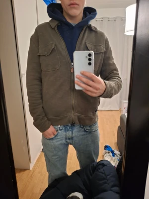 Olivgrön Morris jacka - Olivgrön jacka från Morris med två bröstfickor med lock och dragkedja framtill. Jackan har en klassisk krage och är tillverkad i mjuk bomull. Perfekt för lager-på-lager och grisch stil.