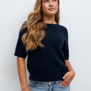 Mörkblå stickad tröja Gina Tricot - Snygg mörkblå stickad tröja från Gina Tricot med korta ärmar och rund hals. Tröjan har en mjuk och fluffig känsla, perfekt för dig som gillar enkel och stilren look. Passar dig som vill ha en chill och trendig vibe.