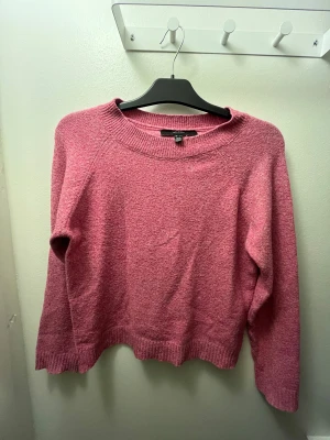 Rosa stickad tröja från Vero Moda - Mysig rosa stickad tröja från Vero Moda i storlek S. Tröjan har en rund halsringning, ribbade muddar vid ärmslut och nederkant samt långärmad passform. Perfekt för dig som gillar en enkel och chill stil med lite färg.