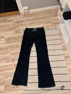 Svarta bootcut jeans från Abrand - Snygga svarta jeans från Abrand med bootcut passform och låg midja. Modellen heter Super Low Kick och har klassiska fem fickor, gulbruna sömmar och dragkedja. Jeansen är i ett stretchigt denimtyg som sitter skönt och ger en schysst siluett.