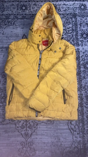 Guess jacka  - Snabb leverans! 🚚 dm för fler bilder! I fantastisk skick! Gul pufferjacka från Guess i storlek XXL med huva och dragkedja där Guess-loggan syns. Jackan är quiltad och har två sidofickor med dragkedja. Perfekt för kalla dagar när du vill sticka ut med färg.