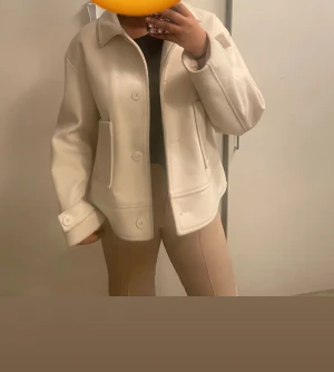 Beige kappa från lager 157 - Snygg beige kappa med klassisk krage och stora, fyrkantiga fickor framtill. Jackan har stora knappar och långärmad passform med knappdetaljer vid ärmslut. Perfekt för lager-på-lager och chill stil.