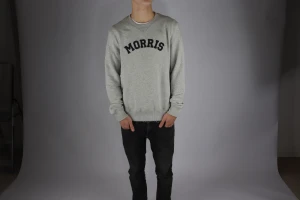 Grå sweatshirt från Morris - Snygg grå sweatshirt från Morris med svart text på bröstet. Tröjan har rund hals, ribbade muddar och lång ärm. Perfekt för dig som gillar enkel och stilren design med en sportig touch.