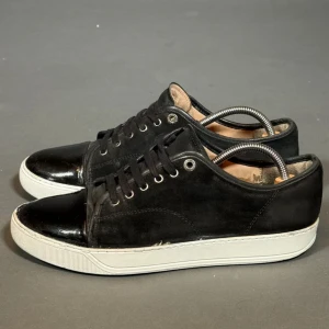 Lanvin Cap Toe  - Klassiska Lanvin Cap Toe i svart med lackad/glansig tå. Storlek 42 (passar även 43). Skorna är använda men fortfarande i bra skick.  Skick: ca 6.5/10 | Defekter: Ej original sula, slitage vid sulan | Medföljer: Inget (endast skorna) | Passform: Normal, något stor i storleken | sulan är målad med vit färg! 