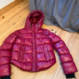 Vinröd vinterjacka  - Vinröd vinterjacka från Superdry i storlek 34. Har en inneficka! Väldigt bra skick!
