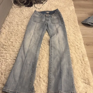 Bootcut jeans Madlady ljusblå EU34 - Säljer ett par ljusblå bootcut jeans från Madlady i storlek EU34. Jeansen har klassisk femficksdesign, snygga bakfickor med knapp och slitningar framtill för en cool vibe. Tillverkade i jeansmaterial med normal passform och breda ben.
