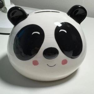 Panda Sparbössa - Hej!  En supergullig sparbössa i form av en panda, gjord av keramik.  Perfekt för både barn och vuxna som vill spara pengar på ett roligt sätt!  Använd ett fåtal gånger och är i mycket fint skick.  Stilren design, både praktisk och dekorativ :)) 🖤🤍