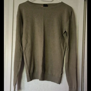 Grön finstickad tröja - En enkel och stilren finstickad tröja från Luca & Lola med rund hals och långa ärmar. Tröjan har en klassisk passform och är tillverkad i bomull. Den har ett litet hål under vänster arm.