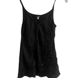 Svart broderad linnetopp Armani jeans - Svart linnetopp från Armani jeans med smala axelband och v-ringning. Toppen har broderade blommor och paljettdetaljer på ena sidan. Tillverkad i ett tunt, lätt material.