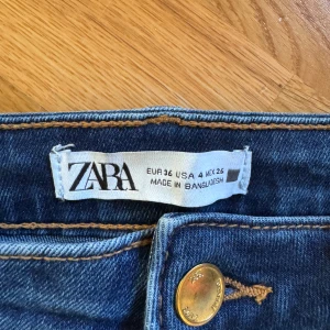Mörkblå skinny jeans från Zara - Snygga mörkblå skinny jeans från Zara med klassisk femficksdesign och gylf med knapp. Jeansen har hög midja och smal passform hela vägen ner. Perfekta till sneakers eller boots och tillverkade i stretchig denim för extra komfort.