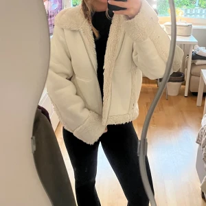 Vit teddyjacka med dragkedja - Säljer en fluffig vit teddyjacka med bred krage och mjuka detaljer vid ärmslut, krage och nederkant. Jackan har en loose passform och stängs med dragkedja framtill. Perfekt för dig som gillar mysiga och trendiga jackor med lite oversized vibe. Köpt på weekday. Mycket varm jacka i gott skick.