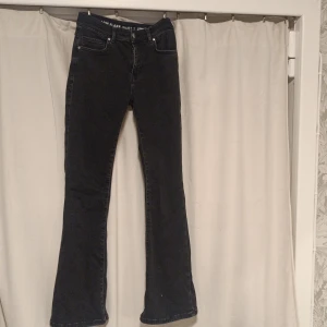 Svarta bootcut jeans low flare - Svarta jeans med bootcut och låg midja från Low Flare. Klassisk femficksmodell med dragkedja och knapp framtill. Jeansen har en snygg mörk tvätt och är tillverkade i jeansmaterial med stretch. Passar dig som gillar en lite utsvängd siluett.