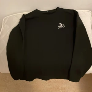 Svart sweatshirt - Svart tröja som har en broderad märke vid bröstet och ser väldigt snyggt ut bra till streetwear style 