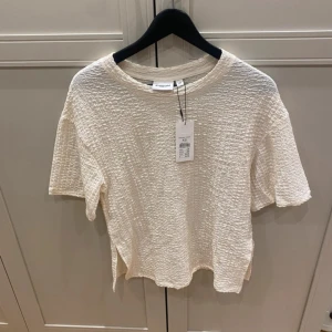 Krämvit strukturerad topp från Kappahl - Säljer en krämvit topp från Kappahl i storlek XS. Toppen har en cool strukturerad yta, rund halsringning och korta ärmar. Materialet känns mjukt och har en unik textur som gör den extra intressant. Perfekt för dig som gillar stilrena och moderna plagg.