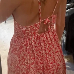 Röd blommig sommarklänning med knyt - Superfin röd klänning med vita blommor och smock upptill. Klänningen har smala axelband, öppen rygg med snygg knytning och är tillverkad i mjuk bomull. Perfekt för varma dagar och har en luftig, avslappnad passform. Klänningen är i stoleken 152 och är från Zara. Skriv såklart till mig ifall du har några frågor eller funderingar!!💕