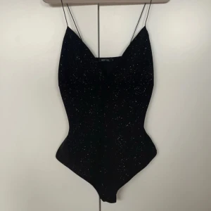 Svart glittrig body från NLY One - Svart glittrig fest body från Nelly, strl L. Oanvänd (utan prislapp). Tvättad och steamad🖤✨