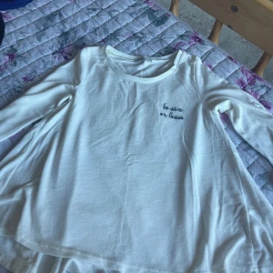 Vit långärmad tröja med text - Vit långärmad tröja med rund halsringning och broderad text 'be nice or leave' på bröstet. Enkel och stilren design, perfekt att matcha med jeans eller kjol. Mjuk och skön bomullskänsla.