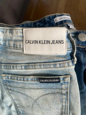 Calvin Klein ljusblå och blå jeans - Två par Calvin Klein Jeans säljes, ett par i ljusblå tvätt och ett i klassisk blå denim. Båda har raka ben, fem fickor och tydliga kontrastsömmar. Jeansen har logotyp på bakfickan och metallknappar med märkning. Perfekt passform och snygg stil.