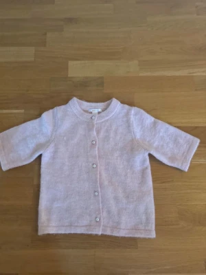 Ljusrosa kofta från Gina Tricot - Superfin ljusrosa kofta från Gina Tricot i mjukt stickat material. Koftan har rund hals, pärlknappar framtill och trekvartsärmar. Perfekt att slänga över en topp för en chill och söt look. Passar dig som gillar mjuka pasteller och klassiska detaljer. Från gina tricot young storlek 146/152.