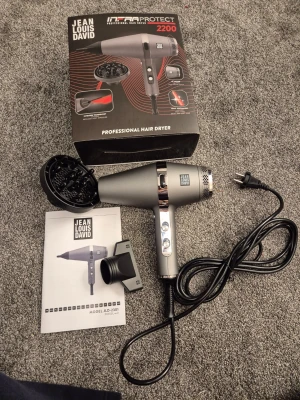 Jean Louis David InfraProtect 2200 Professional Hair Dryer - Den är helt ny oanvänd... Kraftfull hårfön med 2200W, infraröd teknologi och AC-motor för lång livslängd. Utrustad med jonisk turmalin för extra glans och minskad friss. Levereras med diffuser och stylingmunstycke. Produkten ser ut att vara i mycket gott skick, komplett med originalförpackning och manual.