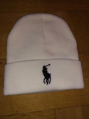 Ralph Lauren mössa  - Säljer en vit Ralph Lauren-mössa! Den är perfekt för att hålla dig varm och stilfull i vinter. Enkel och stilren design som passar till allt! Denna mössa är ett måste i vintergarderoben. Hör av dig om du vill veta mer! ❄️🧢✨