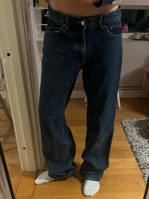 Lågmidjade Marinblåa baggyjeans från Gina tricot  - Säljer ett par Lågmidjade blå baggyjeans från Gina tricot i storlek 38. Modellen har breda ben och klassisk femficksdesign med raka bakfickor. Jeansen är tillverkade i jeansmaterial och har en mörkblå tvätt med kontrastsömmar. Nypris 499 men säljs inte längre så säljer för 200, andvända typ 2 gånger 
