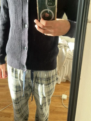 Navy blue ribbad kofta med knappar - Säljer en svart ribbad kofta med klassisk krage och knäppning framtill. Koftan har långa ärmar och är tillverkad i ett stickat material som känns mjukt och skönt. Perfekt att slänga på sig när det är lite kyligt ute.