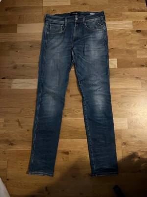 Replay Anbass Hyperflex jeans blå strl w31 l34 - Säljer ett par Replay Anbass Hyperflex jeans i blå tvätt med snygga slitningar och klassiska fem fickor. Jeansen har smal passform och stretchigt material som gör dem riktigt sköna. Perfekt för dig som gillar stilrena och moderna jeans. Liten defekt men syns knappt, kan enkelt lösas med nål och tråd, nytt pris 1699, skriv vid funderingar 