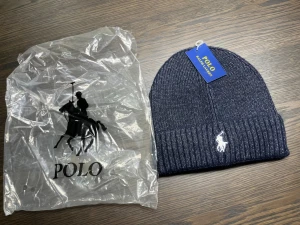 Mörkblå stickad mössa Polo Ralph Lauren - Snygg mörkblå stickad mössa från Polo Ralph Lauren med klassisk ribbad kant och broderad vit logga framtill. Perfekt för att hålla värmen och samtidigt se fräsch ut. Stilren design som passar till de flesta jackor och outfits.