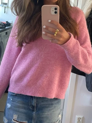 Rosa stickad tröja  - Mysig rosa stickad tröja med rund hals och långa ärmar. Tröjan har ribbade muddar vid hals, ärmslut och nederkant. 