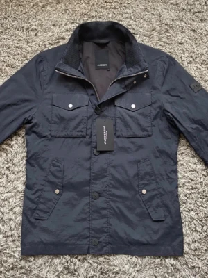 INTRESSEKOLL field jacket j.lindeberg - Intressekoll på denna field jacket från j.lindeberg i skick 8/10. Nypris=4000 kr. Lite smutsig men borde gå bort i tvätt. Storlek M. Mörkblå. Mitt pris 2349 kr! Ej hugget i sten❗️