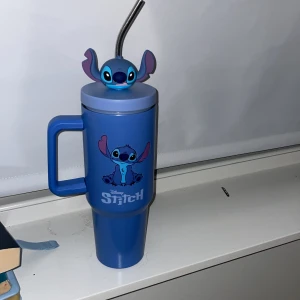 Disney Stitch Termosmugg med Sugrör - Söt blå termosmugg med Stitch-motiv, handtag och lock med 3D Stitch-figur. Inkluderar metalliskt sugrör. Muggen är i mycket fint skick, perfekt för både varma och kalla drycker. Officiell Disney-produkt, idealisk för fans av Lilo & Stitch.