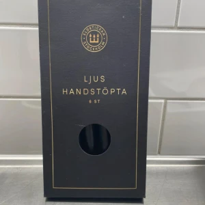 Ljus Handstöpta Svarta 6 st - Elegant förpackning med 6 handstöpta svarta ljus från Eldstickan Stockholm. Perfekt för stilfull inredning och mysiga kvällar. Ljusen är nya och obrutna i originalförpackning, passar både till fest och vardag.