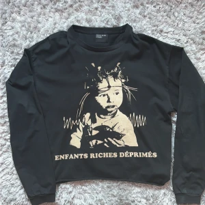 ERD Svart långärmad tröja Enfants Riches Déprimés Storlek M - Svart långärmad tröja från Enfants Riches Déprimés med beige tryck framtill. Storlek M! Tröjan är i 100% bomull och har en cropped/wide passform med rund hals. Perfekt för dig som gillar  unik streetwear. Bra kondition.