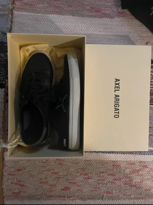 Svarta sneakers Axel Arigato skinn - Svarta sneakers från Axel Arigato med vit platt sula och snörning. Skorna är i skinn med mockadetaljer vid tån och har en broderad fågel på sidan. Bilderna är inte mina och köpte av någon annan på vinted💞 jätte bra skick!! Pris kan diskuteras vid snabb köp